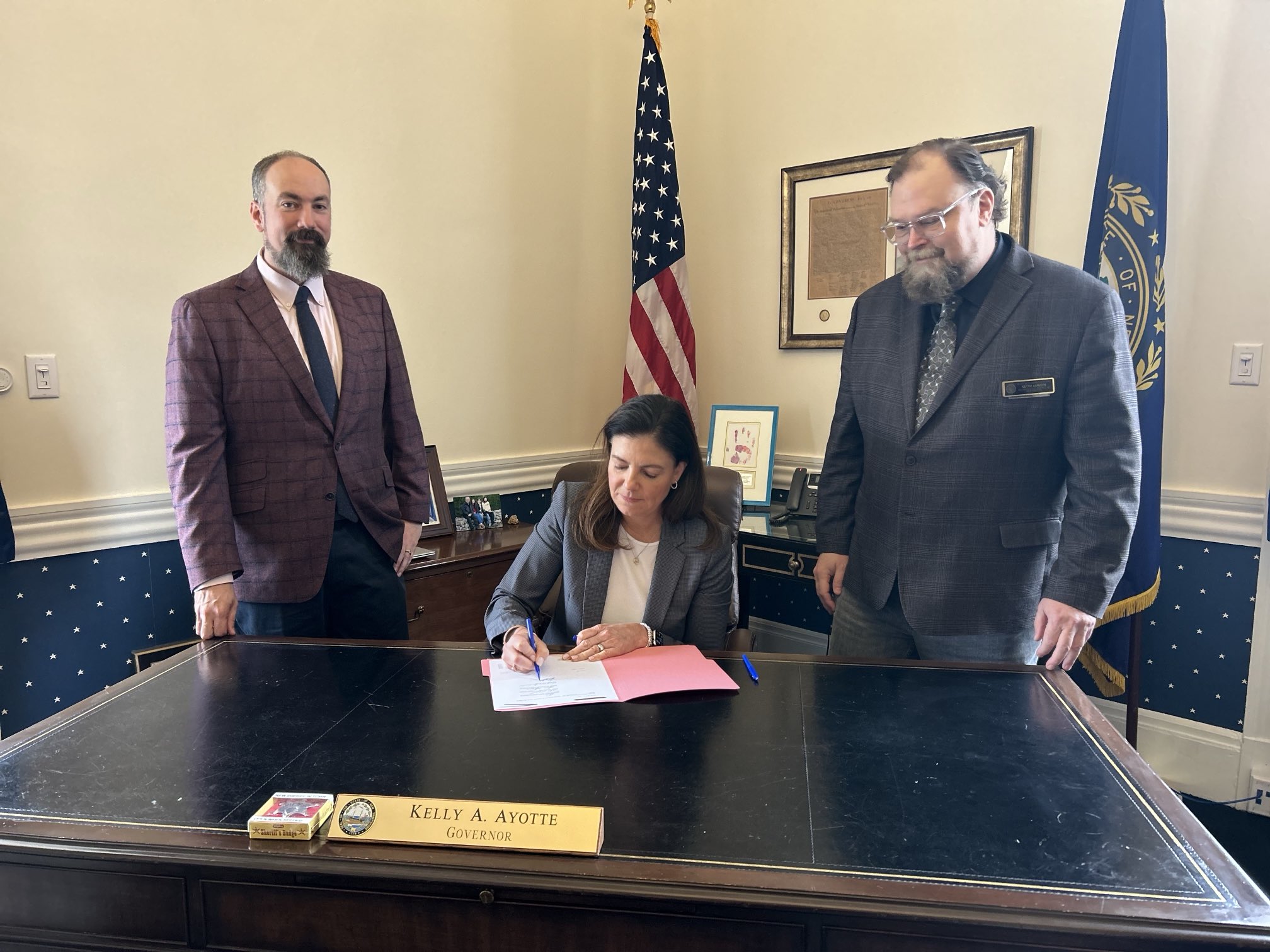 Gov. Kelly Ayotte signs a bill as Jason Osborne looks on